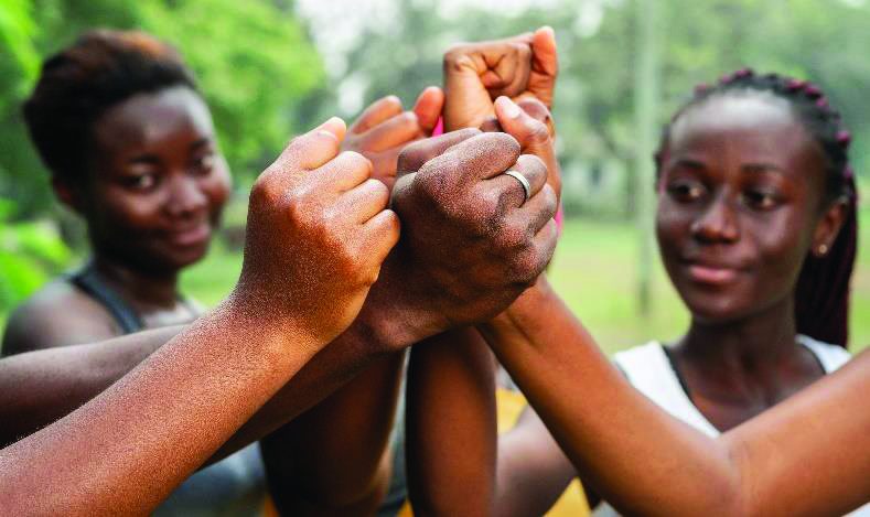 Young women from a PMDF community programme joining hands together