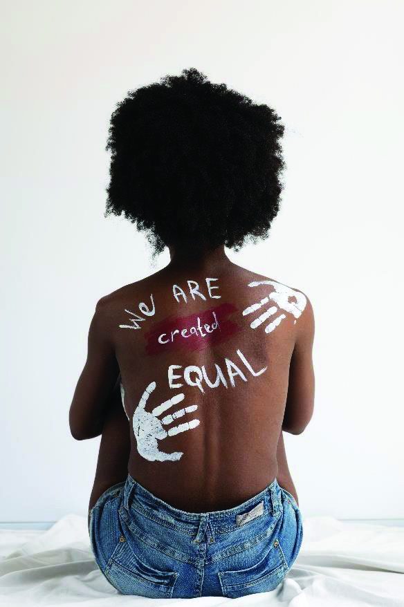 A young woman with We Are Created Equal painted on her back, symbolising the fight against gender-based violence
