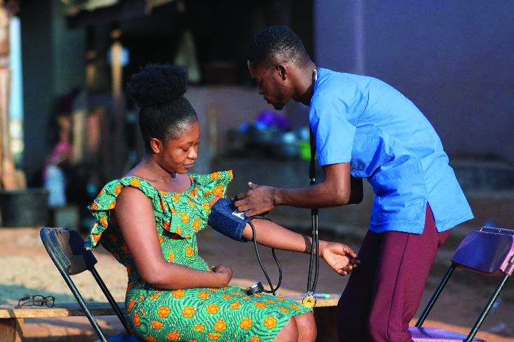 A community health worker checking a patient's blood pressure